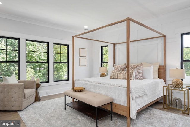 bedroom featuring ornamental molding, wood finished floors, and a decorative wall