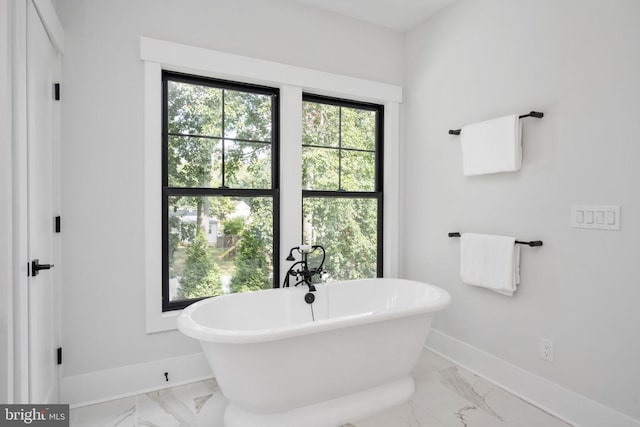 full bathroom with a freestanding bath, marble finish floor, and baseboards