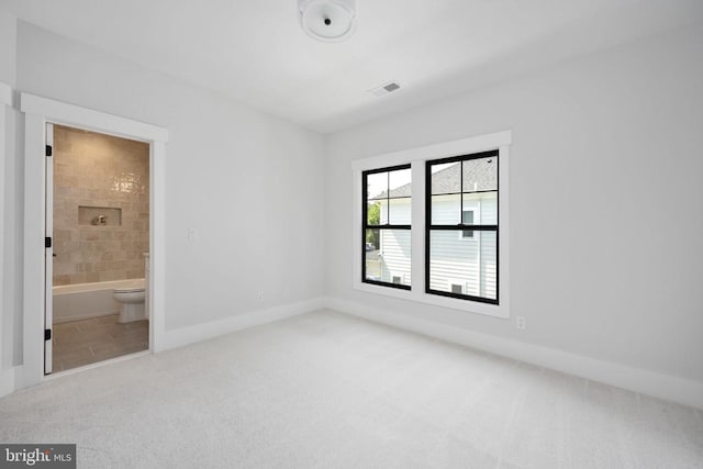 unfurnished bedroom with light carpet, baseboards, visible vents, and connected bathroom