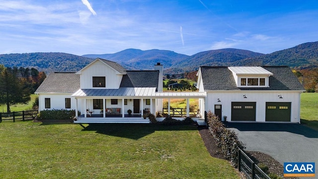 exterior space featuring a garage, a mountain view, covered porch, and a front lawn