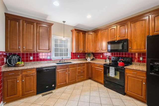 kitchen featuring sink, tasteful backsplash, decorative light fixtures, light stone countertops, and black appliances