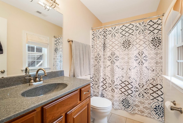 bathroom with tile patterned floors, vanity, toilet, and a wealth of natural light