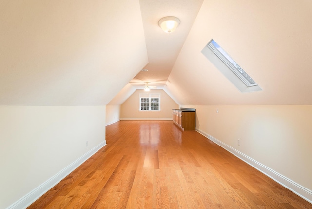 bonus room with vaulted ceiling with skylight and light hardwood / wood-style flooring