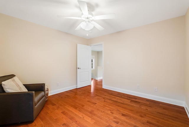 living area with wood-type flooring and ceiling fan