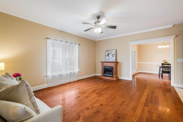 living room featuring crown molding, wood-type flooring, and ceiling fan with notable chandelier