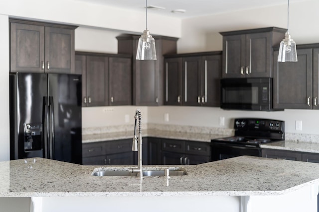 kitchen with black appliances, a kitchen island with sink, pendant lighting, and a sink