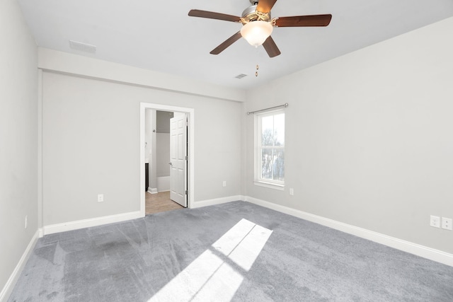 unfurnished bedroom with ensuite bathroom, a ceiling fan, visible vents, baseboards, and carpet