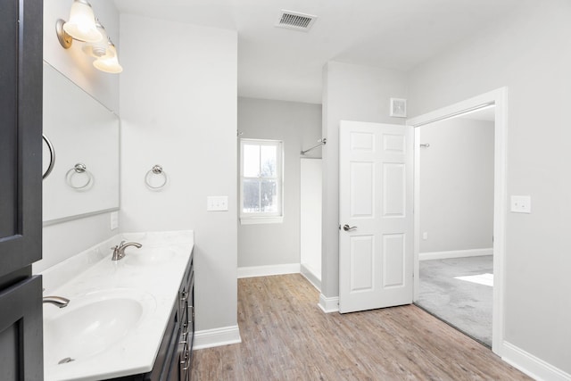 full bath with double vanity, visible vents, a sink, and wood finished floors