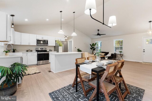 dining space with sink, light hardwood / wood-style flooring, high vaulted ceiling, and ceiling fan