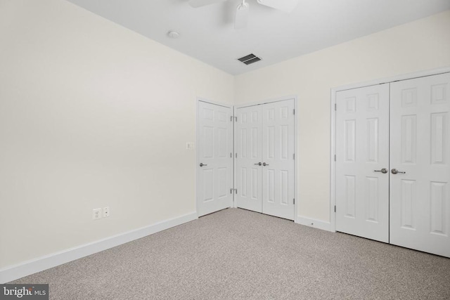 unfurnished bedroom with visible vents, two closets, ceiling fan, baseboards, and carpet floors