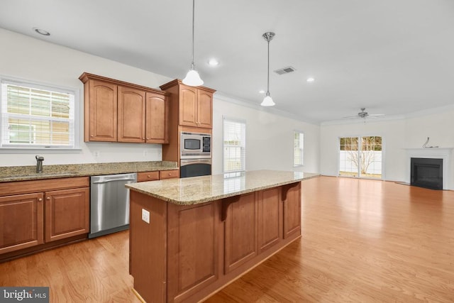 kitchen featuring visible vents, light wood-style flooring, a sink, appliances with stainless steel finishes, and a fireplace