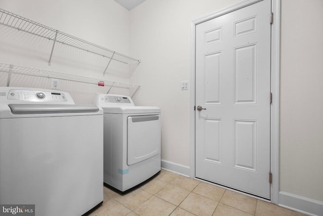 laundry area with light tile patterned floors, baseboards, washing machine and dryer, and laundry area