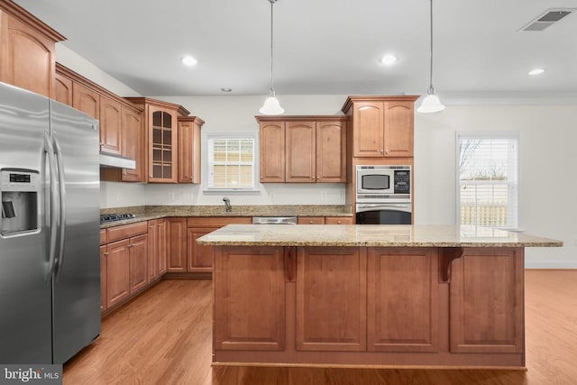 kitchen with light stone counters, visible vents, stainless steel appliances, and glass insert cabinets