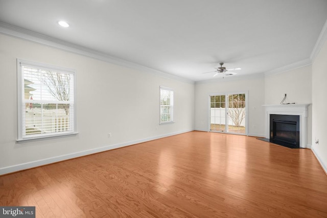 unfurnished living room with a fireplace with flush hearth, wood finished floors, baseboards, and ornamental molding