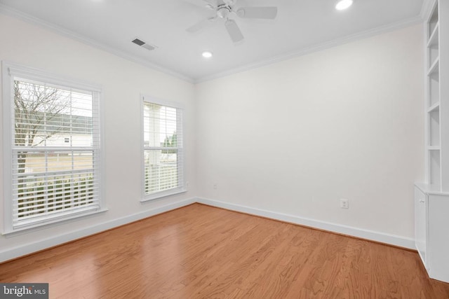 spare room with visible vents, baseboards, light wood-style floors, and ornamental molding