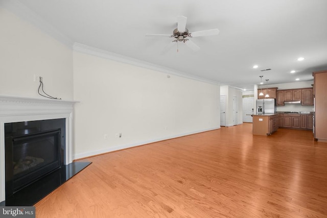 unfurnished living room featuring a glass covered fireplace, light wood-style flooring, baseboards, and ornamental molding