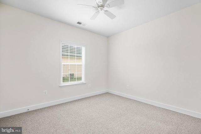 carpeted spare room with visible vents, baseboards, and a ceiling fan