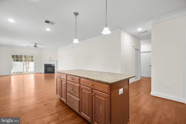 kitchen with a fireplace, crown molding, light wood-style floors, and visible vents