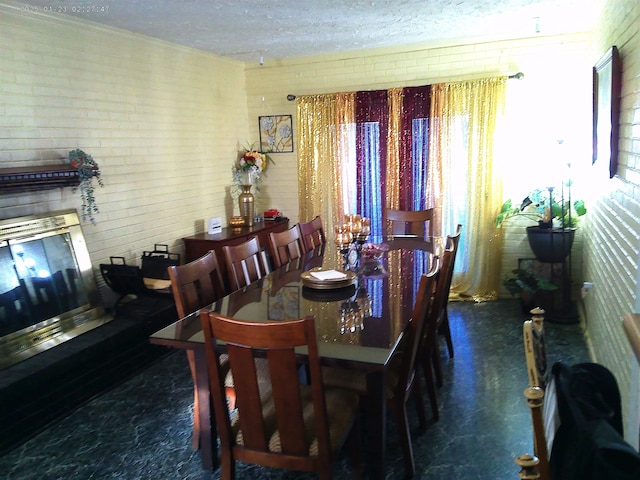 dining room featuring a fireplace, a textured ceiling, and brick wall