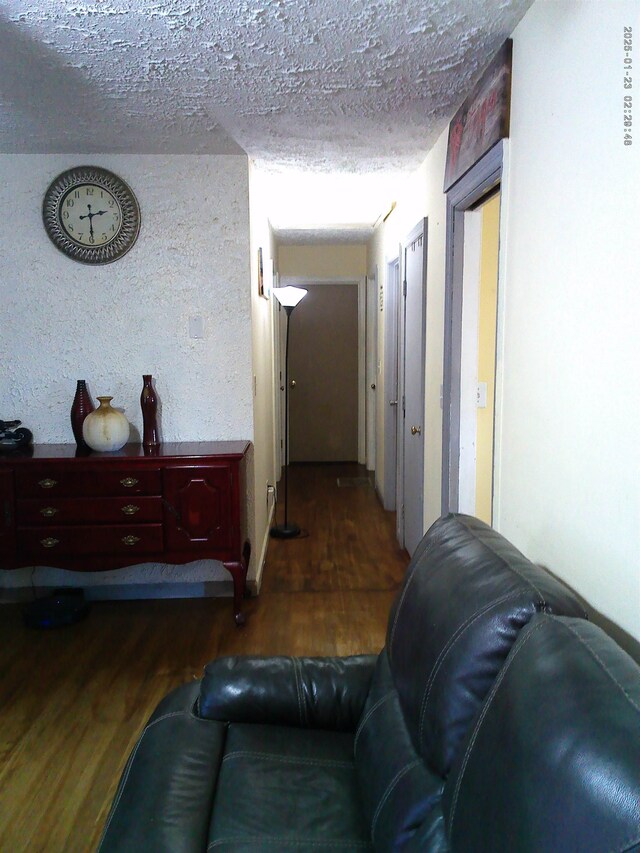 corridor featuring dark wood-type flooring and a textured ceiling