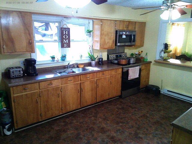 kitchen with ceiling fan, appliances with stainless steel finishes, a baseboard radiator, and sink