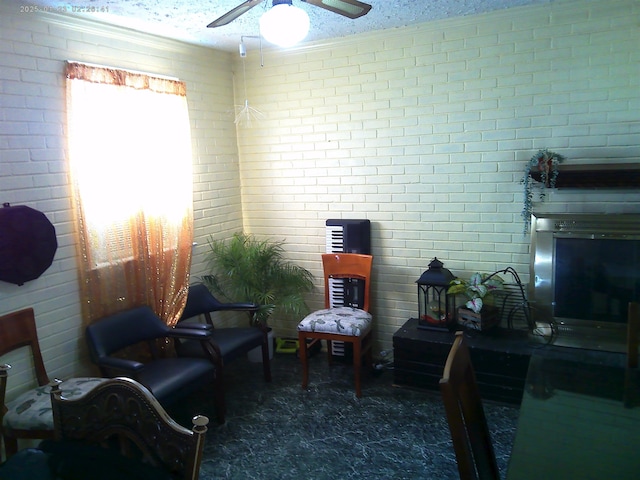 sitting room featuring ceiling fan, crown molding, a textured ceiling, and brick wall