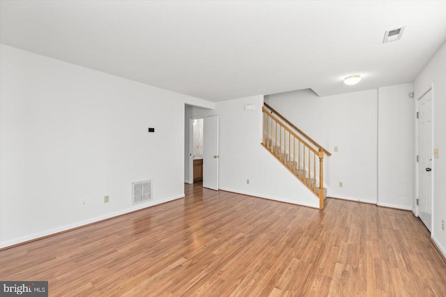 unfurnished living room with visible vents, light wood-style flooring, and stairs