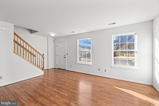 foyer entrance featuring visible vents, a healthy amount of sunlight, stairway, and wood finished floors