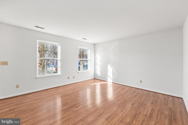 unfurnished room with visible vents, baseboards, and wood finished floors