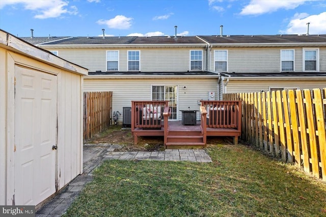 back of property with a yard, a deck, and a fenced backyard