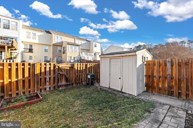 view of yard with a residential view, a fenced backyard, a storage unit, a vegetable garden, and a gate