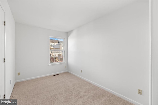 carpeted spare room featuring visible vents and baseboards