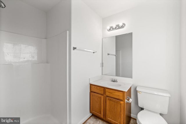 bathroom with baseboards, toilet, walk in shower, and vanity