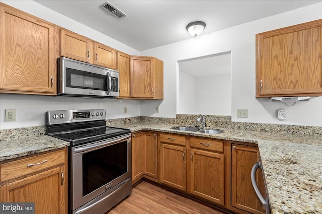 kitchen with visible vents, brown cabinets, stainless steel appliances, and a sink