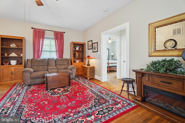 living area featuring visible vents, ceiling fan, and wood finished floors