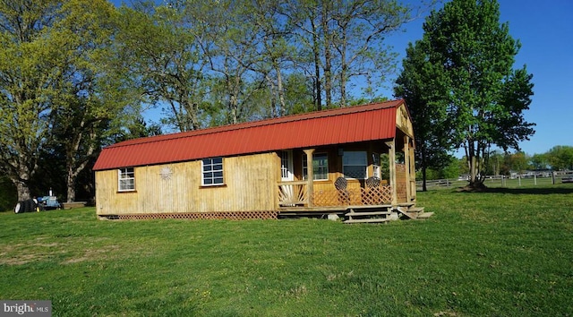 exterior space with a front lawn, a gambrel roof, and metal roof