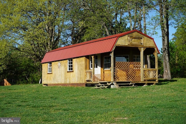 exterior space with metal roof, a gambrel roof, and a front lawn