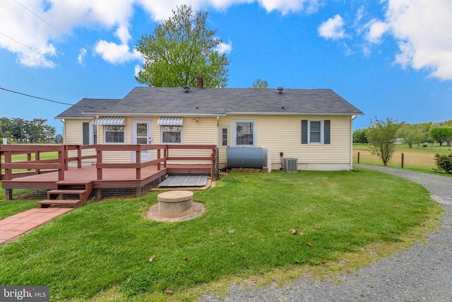 rear view of house featuring a fire pit, a wooden deck, central AC, a yard, and heating fuel