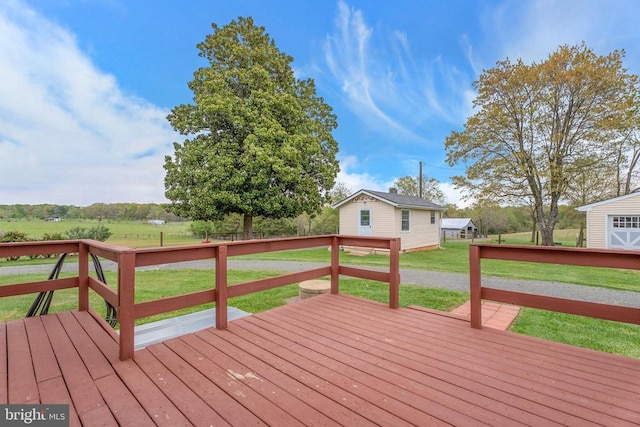 wooden terrace featuring an outdoor structure, a yard, and a rural view