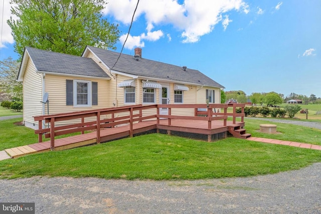 back of property featuring a deck, a chimney, and a yard