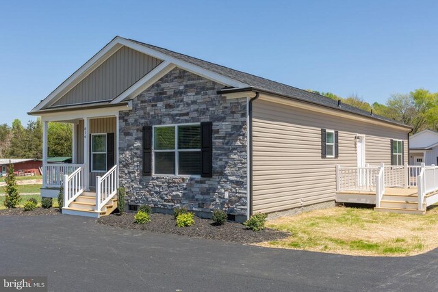 view of front of property with board and batten siding, a wooden deck, and stone siding