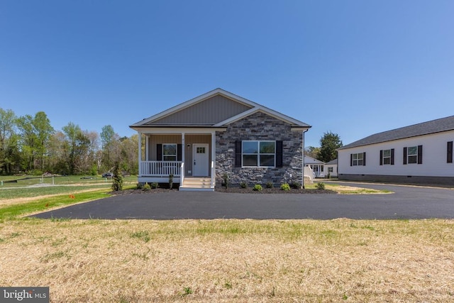 craftsman-style home with a front lawn, stone siding, board and batten siding, and covered porch