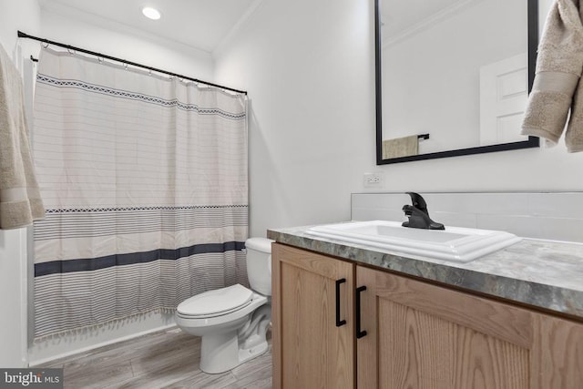 bathroom featuring wood finished floors, toilet, ornamental molding, and vanity