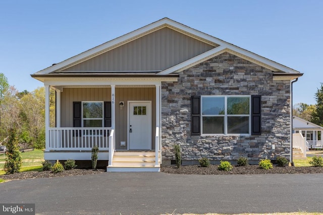 craftsman inspired home featuring covered porch, board and batten siding, and stone siding