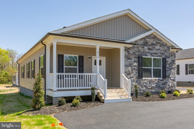 view of front of property featuring a porch, crawl space, stone siding, and board and batten siding
