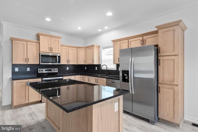 kitchen featuring light brown cabinets, stainless steel appliances, crown molding, and a sink