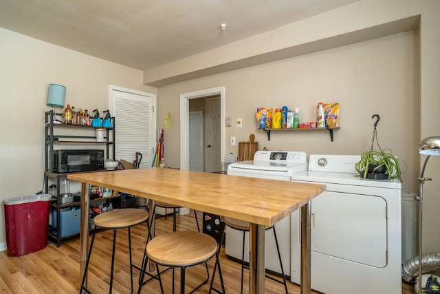 kitchen with black microwave, washing machine and dryer, light countertops, light wood finished floors, and a glass covered fireplace