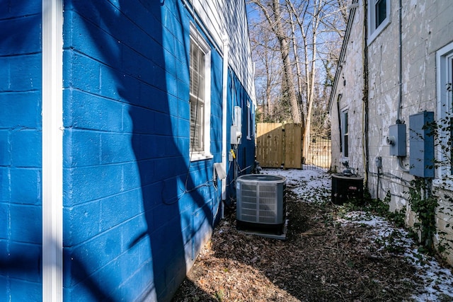 view of home's exterior featuring central AC, concrete block siding, and fence