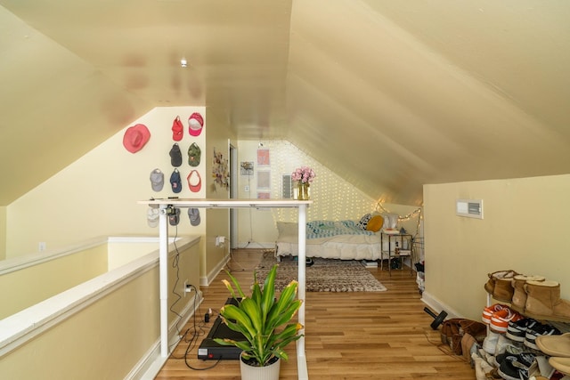 bedroom with baseboards, vaulted ceiling, and wood finished floors