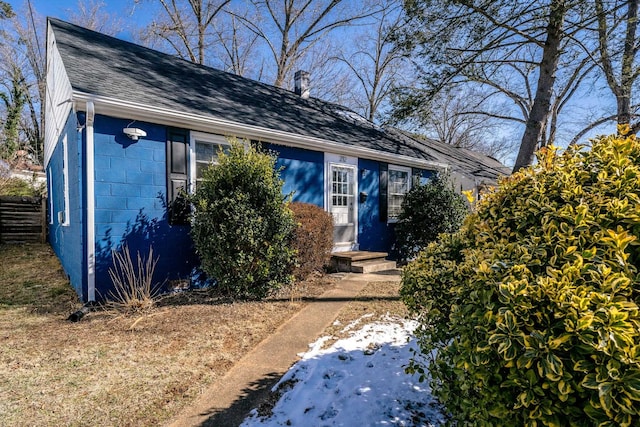 view of front of home featuring concrete block siding and roof with shingles